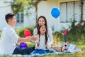 Happy family having fun outdoor sitting on picnic blanket playing balloons