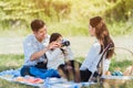 Happy family having fun outdoor together sitting on the grass party with shooting photos by retro camera a picnic Royalty Free Stock Photo