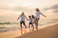 Happy family having fun running on a sandy beach at sunset time Royalty Free Stock Photo