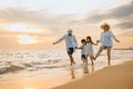 Happy family having fun running on a sandy beach at sunset time Royalty Free Stock Photo