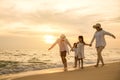 Happy family having fun running on a sandy beach at sunset time Royalty Free Stock Photo