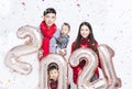 Happy family having fun with sign 2021 made of silver balloons for new year