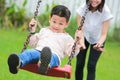 Happy family having fun on a swing ride at a garden. Royalty Free Stock Photo