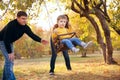 Happy family having fun on a swing ride at a garden a autumn day Royalty Free Stock Photo