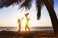 Happy family having fun under palm on sunset beach