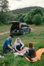 Happy family having lunch and drink tea. camping, weekend, picnic. man, woman, girl, Crossover, SUV car on backgrond, vertical Royalty Free Stock Photo