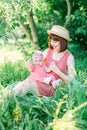 A happy family having a picnic in the green garden in a sunny spring day: a beautiful smiling mother sitting on green