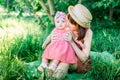 A happy family having a picnic in the green garden in a sunny spring day: a beautiful smiling mother sitting on green