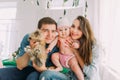 The happy family is holding the baby and the rabbit while sitting in the childroom.