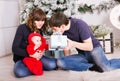 Happy family holding Christmas gifts near Xmas tree. Baby, mother and father having fun at home Royalty Free Stock Photo