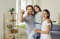 Happy family holding house keys and looking cheerful at camera standing in new apartment. Royalty Free Stock Photo
