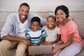 Happy family holding laptop while sitting on sofa at home Royalty Free Stock Photo