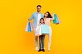 Happy family holding shopping bags and smiling, parents and their daughter posing with colorful paper shoppers Royalty Free Stock Photo