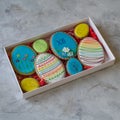 Happy family holiday, presents in box , gingerbread easter bright cookies in form eggs. Festive cookies in white box on gray