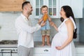 Happy family in home kitchen married couple with small child and pregnant woman Royalty Free Stock Photo