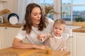 Happy family at home. Mother feeding baby in kitchen. Little boy with messy funny face eats healthy food. Child learns Royalty Free Stock Photo