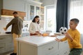 Parents cooking on kitchen while boy son playing soccer ball Royalty Free Stock Photo