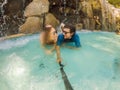 Happy family on honeymoon holidays - just married loving couple swimming with fun in waterfall pool. Active lifestyle Royalty Free Stock Photo