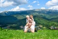Happy family: joyful father, mother and two sons are lying on the green grass against the background of the forest, mountains and Royalty Free Stock Photo