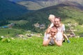 Happy family: joyful father, mother and two sons are lying on the green grass against the background of the forest, mountains and Royalty Free Stock Photo