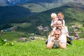 Happy family: joyful father, mother and two sons are lying on the green grass against the background of the forest, mountains and Royalty Free Stock Photo