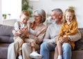 Happy family joyful little children hugging embracing with positive senior grandparents at home Royalty Free Stock Photo