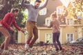 Happy family jumping at fall leaves at backyard. Royalty Free Stock Photo