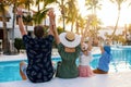 happy family with kids and arms raised having fun by the swimming pool at tropical resort hotel. summer vacation Royalty Free Stock Photo