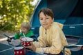 Happy family, kids, boy brothers and a dog, having breakfast in front of pitched tent on beach, while wild camping in Norway, Royalty Free Stock Photo