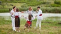 Happy family with kids in traditional romanian dress in a countryside, park, dancing outside. Royalty Free Stock Photo