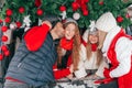 Happy family kissing kids on Christmas family party, sisters are laughing. Family have fun in car trunk among red Royalty Free Stock Photo