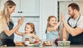 Happy family in kitchen, cooking with kids and high five with success, learning and nutrition with parents. Mom, dad and Royalty Free Stock Photo