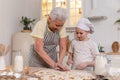 Happy family in kitchen. Grandmother granddaughter child cutting cookies of dough on kitchen table together. Grandma