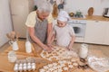 Happy family in kitchen. Grandmother granddaughter child cutting cookies of dough on kitchen table together. Grandma