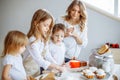 Happy family in the kitchen. Mother and her cute kids are cooking cookies.