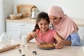 Happy Family In Kitchen. Muslim Mom And Daughter Cutting Homemade Pie Royalty Free Stock Photo