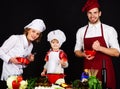 Happy family in kitchen preparing healthy food. Adorable son in chef hat with parents cooking together homemade food Royalty Free Stock Photo