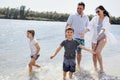 Happy family on the lake or river. Son and daughter run on the water and splash on their smiling parents Royalty Free Stock Photo