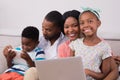 Happy family with laptop and digital tablet sitting on sofa Royalty Free Stock Photo