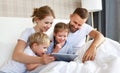 Happy family laughing with tablet computer in bed at home. watching movies and   Internet Royalty Free Stock Photo