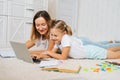 Happy family learning from home together lying on floor in children room looking on laptop screen. Royalty Free Stock Photo