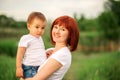 Happy family leisure outdoors. Portrait of smiling young woman holding little toddler son in arms, green background Royalty Free Stock Photo