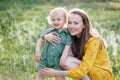 Happy family leisure outdoors. Portrait of smiling young woman holding little toddler son in arms. They are sitting on the green Royalty Free Stock Photo