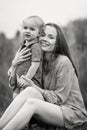 Happy family leisure outdoors. Portrait of smiling young woman holding little toddler son in arms. They are sitting on the green Royalty Free Stock Photo