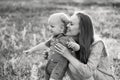 Happy family leisure outdoors. Portrait of smiling young woman holding little toddler son in arms. They are sitting on the green Royalty Free Stock Photo