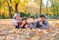 Happy family lies in autumn city park on fallen leaves. Children and parents posing, smiling, playing and having fun. Bright yello Royalty Free Stock Photo