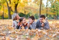 Happy family lies in autumn city park on fallen leaves. Children and parents posing, smiling, playing and having fun. Bright yello Royalty Free Stock Photo