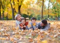 Happy family lies in autumn city park on fallen leaves. Children and parents posing, smiling, playing and having fun. Bright yello Royalty Free Stock Photo