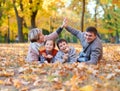 Happy family lies in autumn city park on fallen leaves. Children and parents posing, smiling, playing and having fun. Bright yello Royalty Free Stock Photo