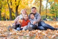 Happy family lies in autumn city park on fallen leaves. Children and parents posing, smiling, playing and having fun. Bright yello Royalty Free Stock Photo